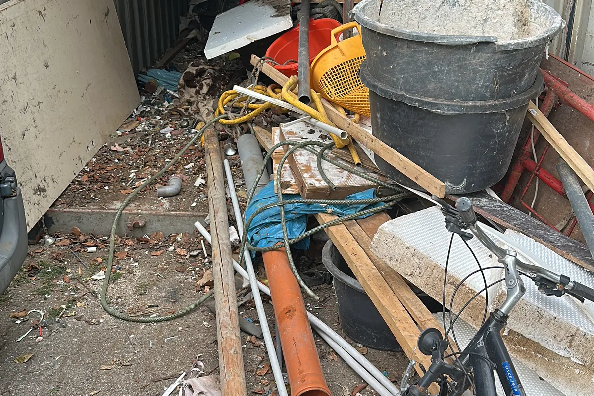 Vollgestellter Garagenbereich mit Fahrrad, Rohren und Metallteilen