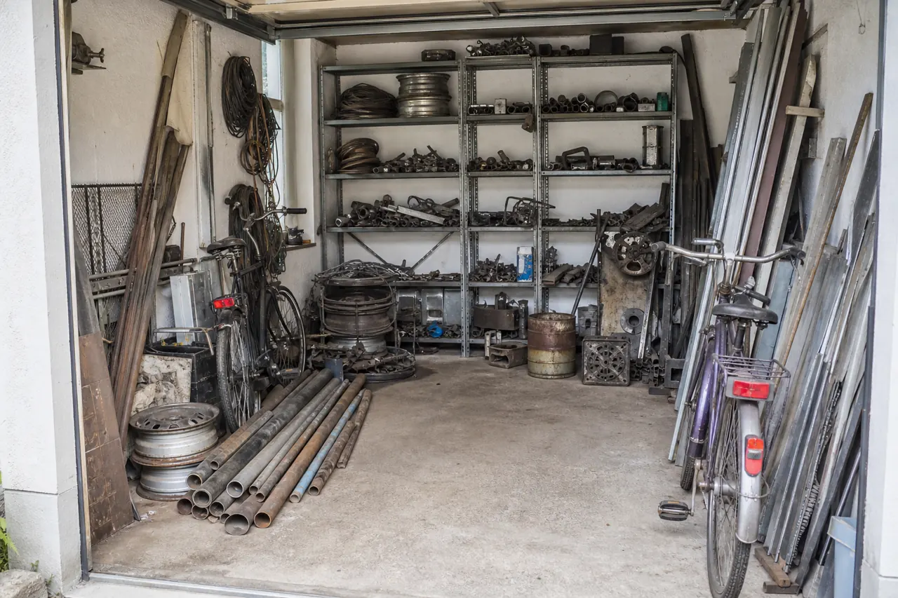 Garage mit Fahrrädern, Metallregalen und Schrott vor der Entrümpelung